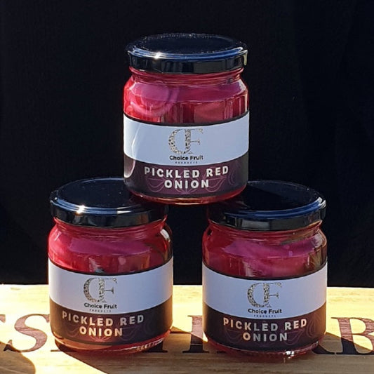 Three jars of pickled red onion on a wooden surface with a black background