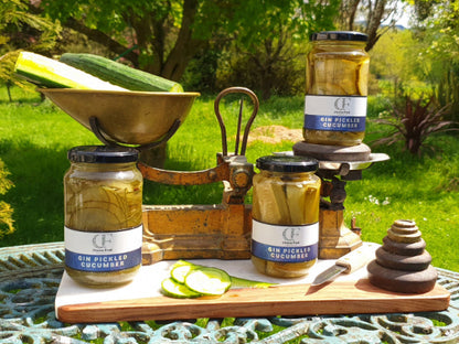 Jars of pickled cucumbers on a wooden board with a garden background