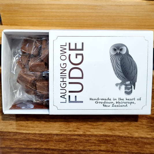A gift box of Laughing Owl brand fudge, showing the box open to reveal individual pieces of fudge wrapped in transparent paper. The box has silver embossing with an owl illustration and text.