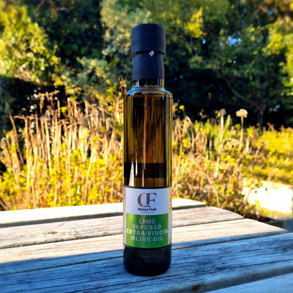 A bottle of Lime Infused Olive Oil by ChoiceFruits, placed on a wooden surface with natural surroundings.