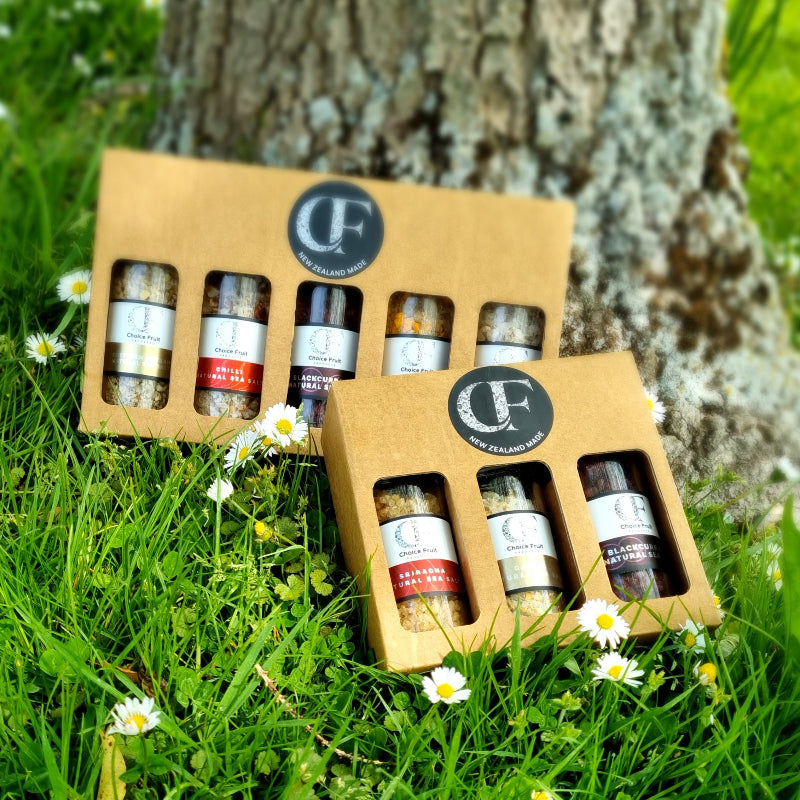 Set of salt bottles in a cardboard box on grass with flowers